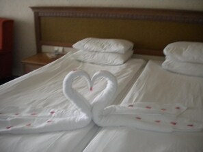 Habitación de hotel con una cama bien tendida y un arreglo de toallas con forma de cisne.