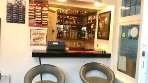 A bar area with two stools, a counter with various bottles, and a wall with posters. - The Southwold (Skegness)