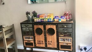 A kitchenette with a vintage design, a television mounted above it, and various food items on the counter. - The Southwold (Skegness)