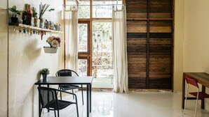 Un comedor con una mesa, sillas, una planta colgante y una puerta de madera.