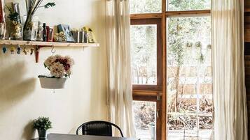 A dining area with a table and chairs, a hanging plant, and a window with curtains.