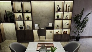 Una sala de reuniones moderna con una mesa de mármol, un juego de ajedrez, plantas en macetas y una estantería con objetos decorativos.