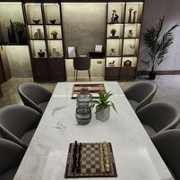 Una sala de reuniones moderna con una mesa de mármol, un juego de ajedrez, plantas en macetas y una estantería con objetos decorativos.