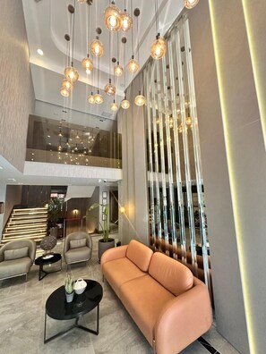 A modern lobby with a sofa, chairs, a coffee table, and pendant lighting. - KIZILKAYA BUSINESS OTEL  (Korfez)