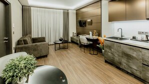 Una cocina moderna con horno empotrado, un comedor con mesa y sillas, y una sala de estar con sofá y planta.