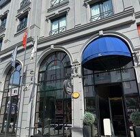 Un edificio con una entrada arqueada grande, un toldo azul y un letrero que indica un hotel.