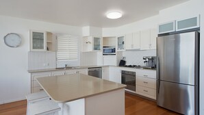 A modern kitchen with white cabinetry, a stainless steel refrigerator, a microwave, and a built-in oven.