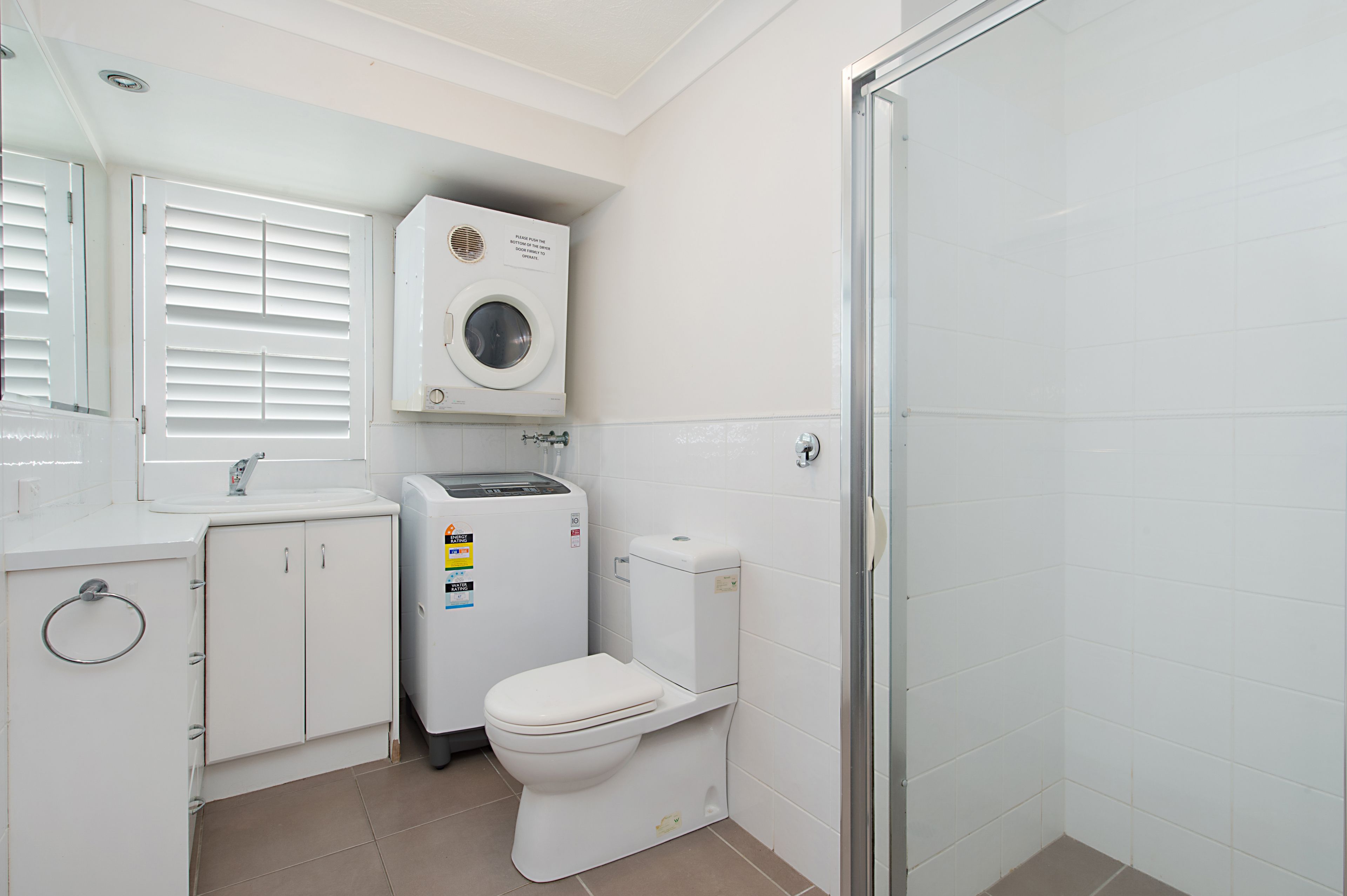 Ein kleines Badezimmer mit Toilette, Waschmaschine und Waschbecken.