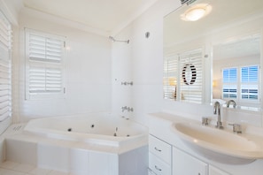 A modern bathroom with a freestanding bathtub, a large vanity with a sink, and a mirror with a decorative frame.