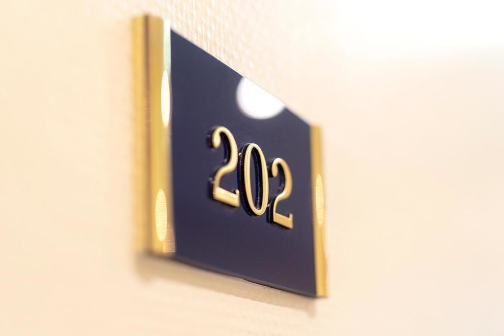Un gros plan d’une plaque indiquant le numéro de chambre, « 202 », sur un mur.
