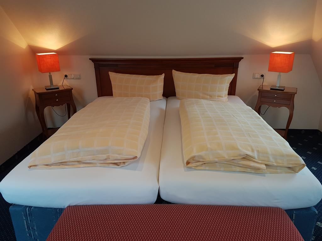 Una cama doble con dos mesitas de noche, cada una con una lámpara.