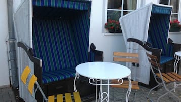 Outdoor seating with striped cushions, a round metal table, and wooden chairs.