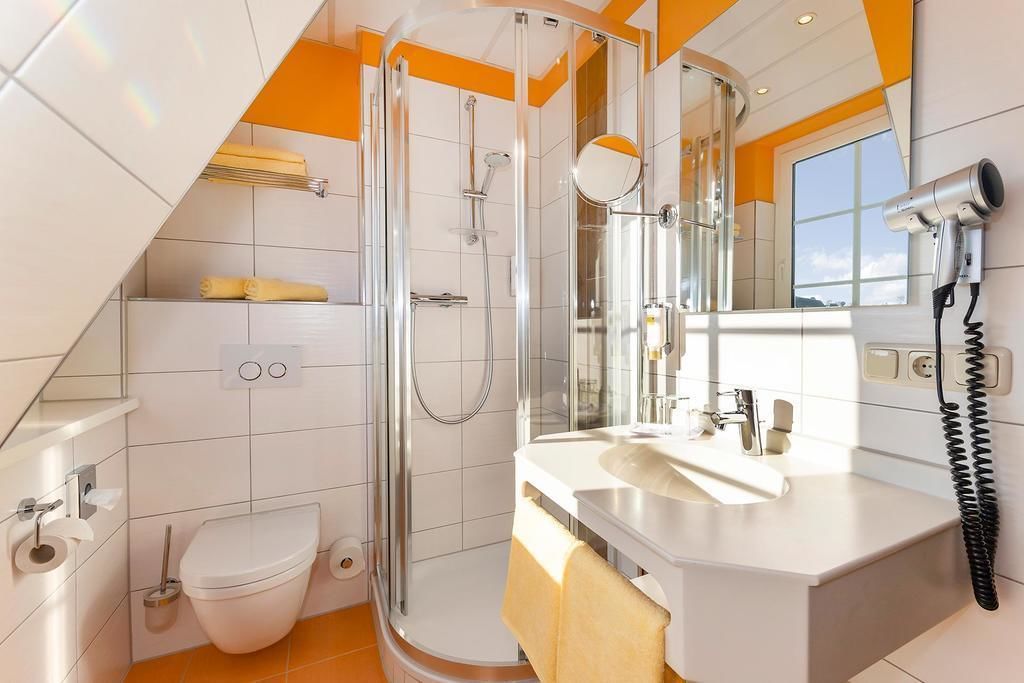 Een moderne badkamer met een douche met glazen wand, een witte wastafel en een spiegel.