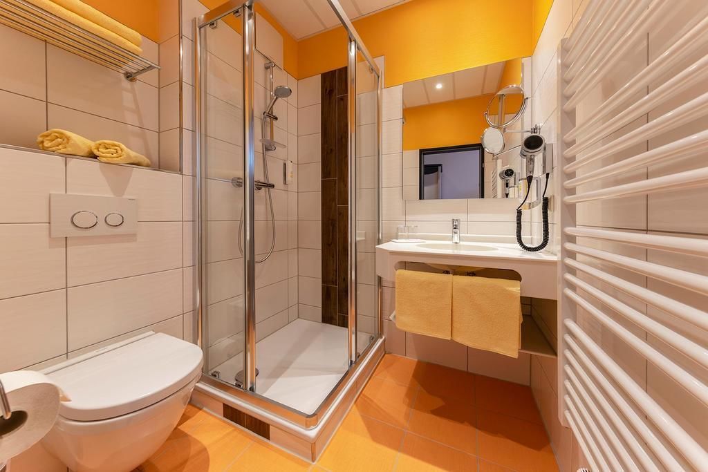 A modern bathroom with a glass-enclosed shower, a toilet, a sink with a mirror, and a towel rack.