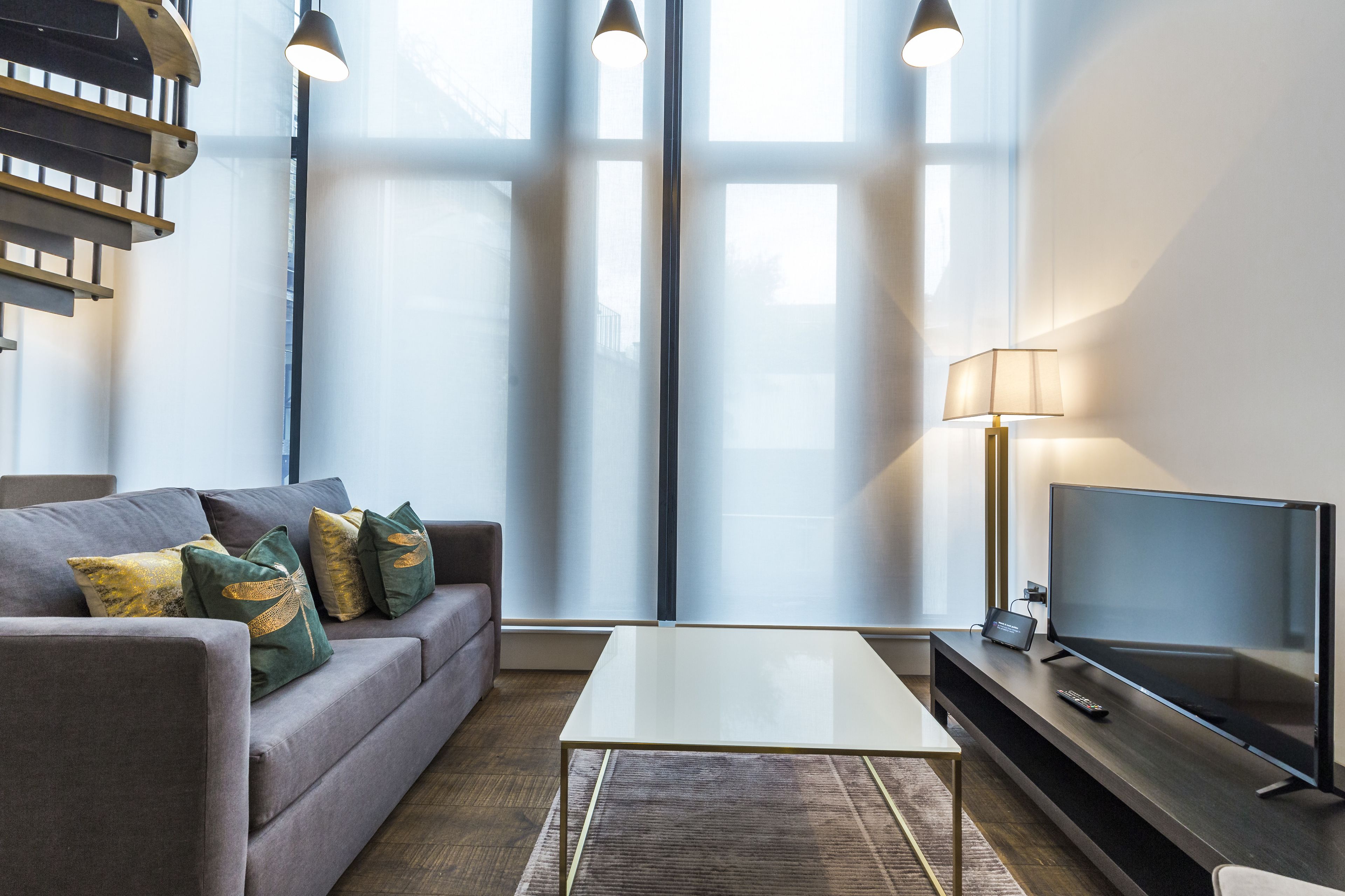 A modern living room with a sofa, a coffee table, a TV, and a lamp.