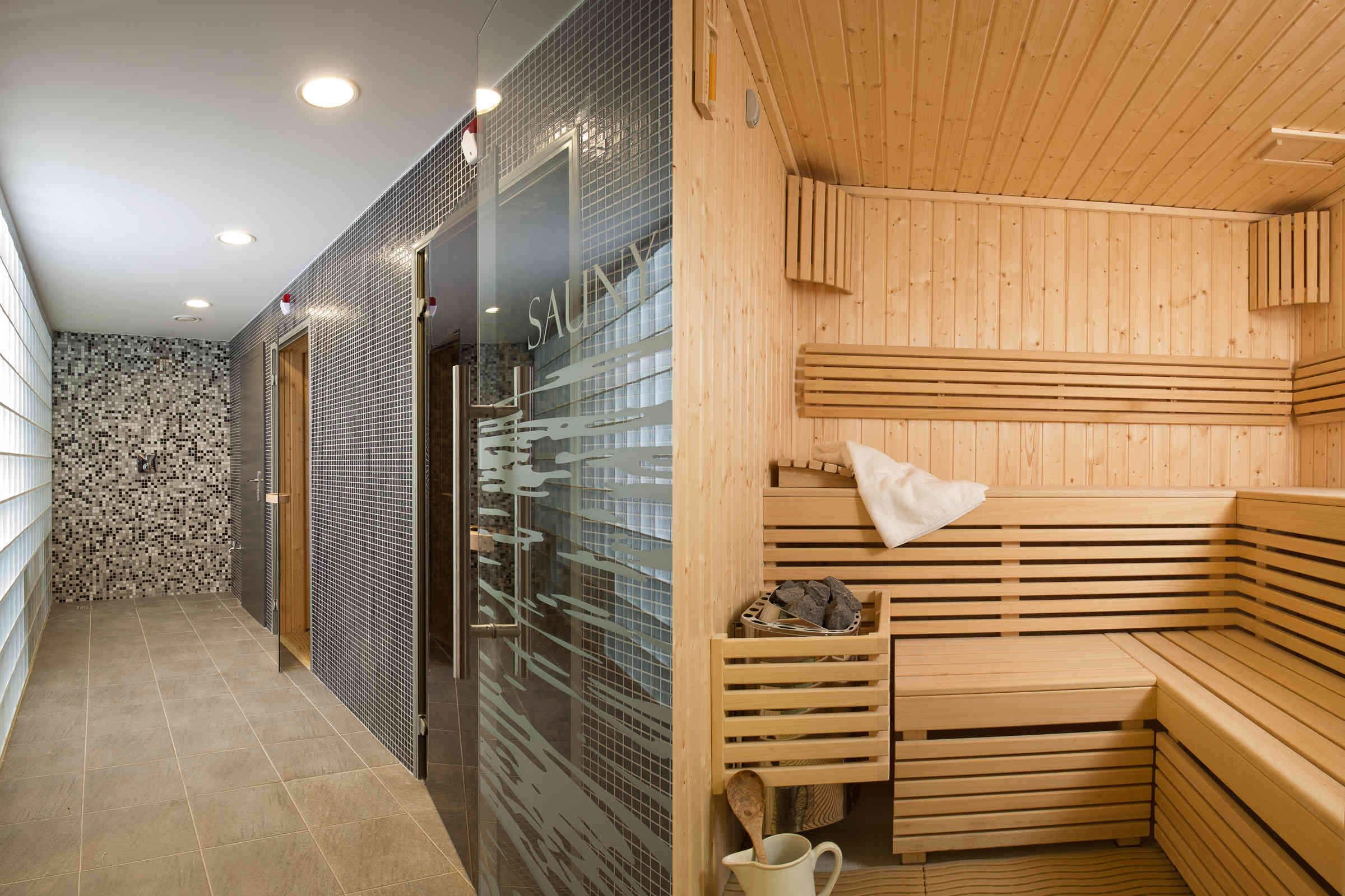 Een sauna met houten banken en een glazen deur, een betegelde muur en vloer.