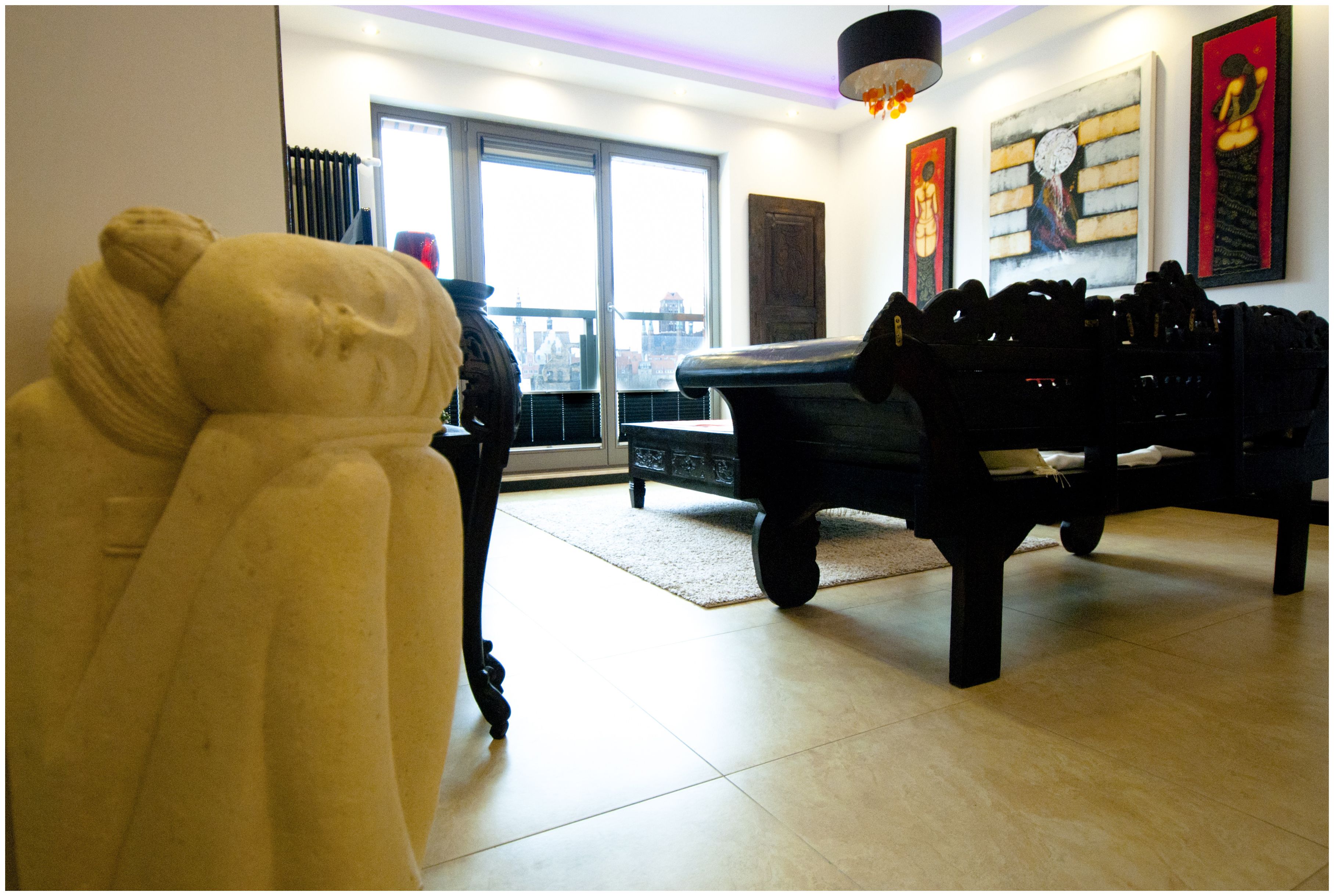 A room with a pool table, a large white sculpture, and artwork on the walls.