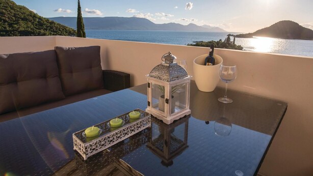 Un balcon avec un canapé, une table sur laquelle se trouve une lanterne, un verre à vin et des bougies.