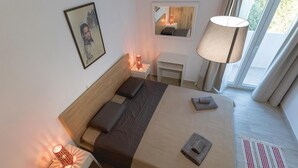 Une chambre d’hôtel moderne équipée d’un lit, de lampes de chevet, d’une table de chevet, d’un miroir et d’une fenêtre avec des rideaux.