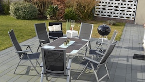An outdoor patio with a table and chairs, a barbecue grill, and a decorative glass. - Holiday house in Duhnen with a large garden and lots of space (Cuxhaven)