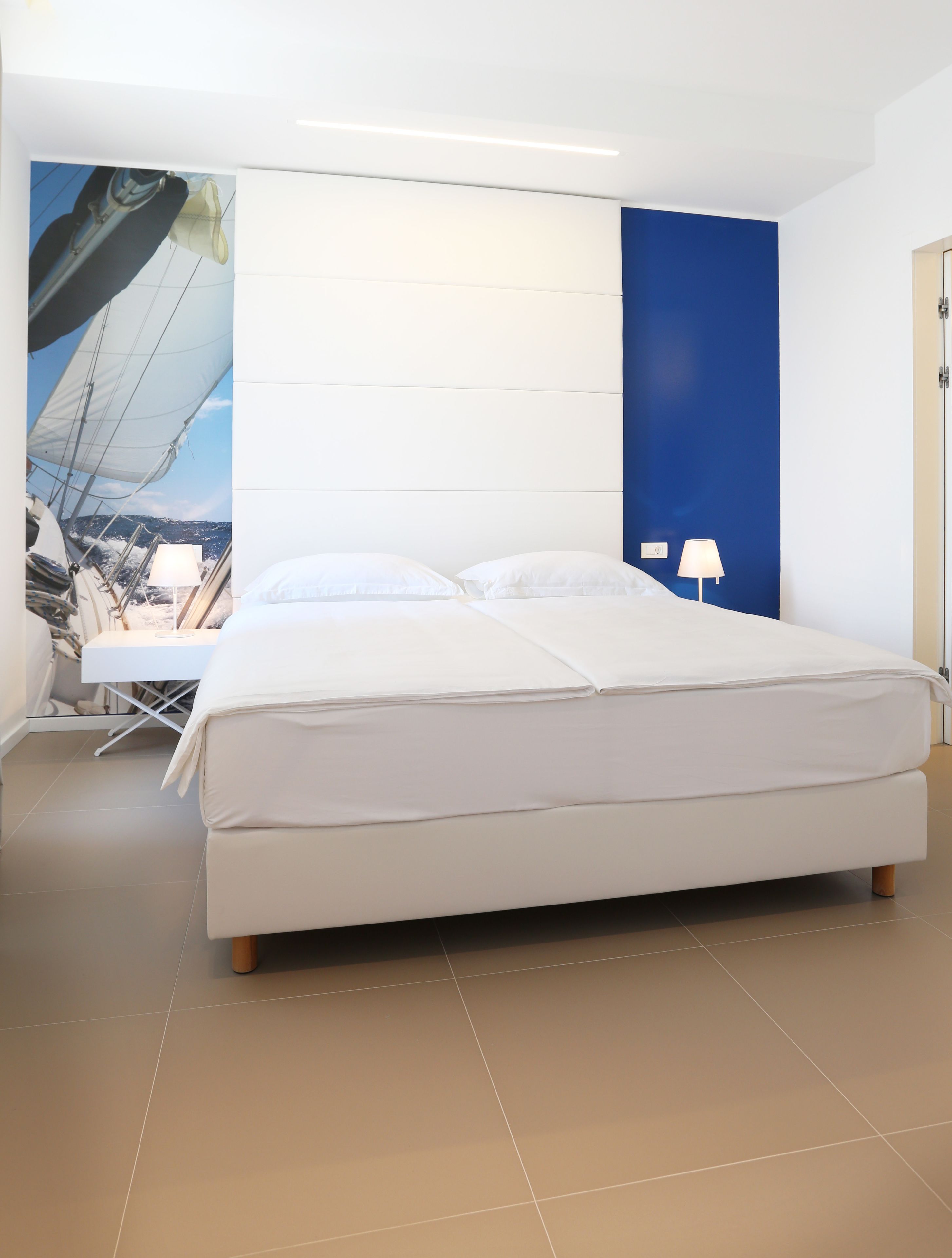A modern bedroom with a large bed, a desk, and a chair.