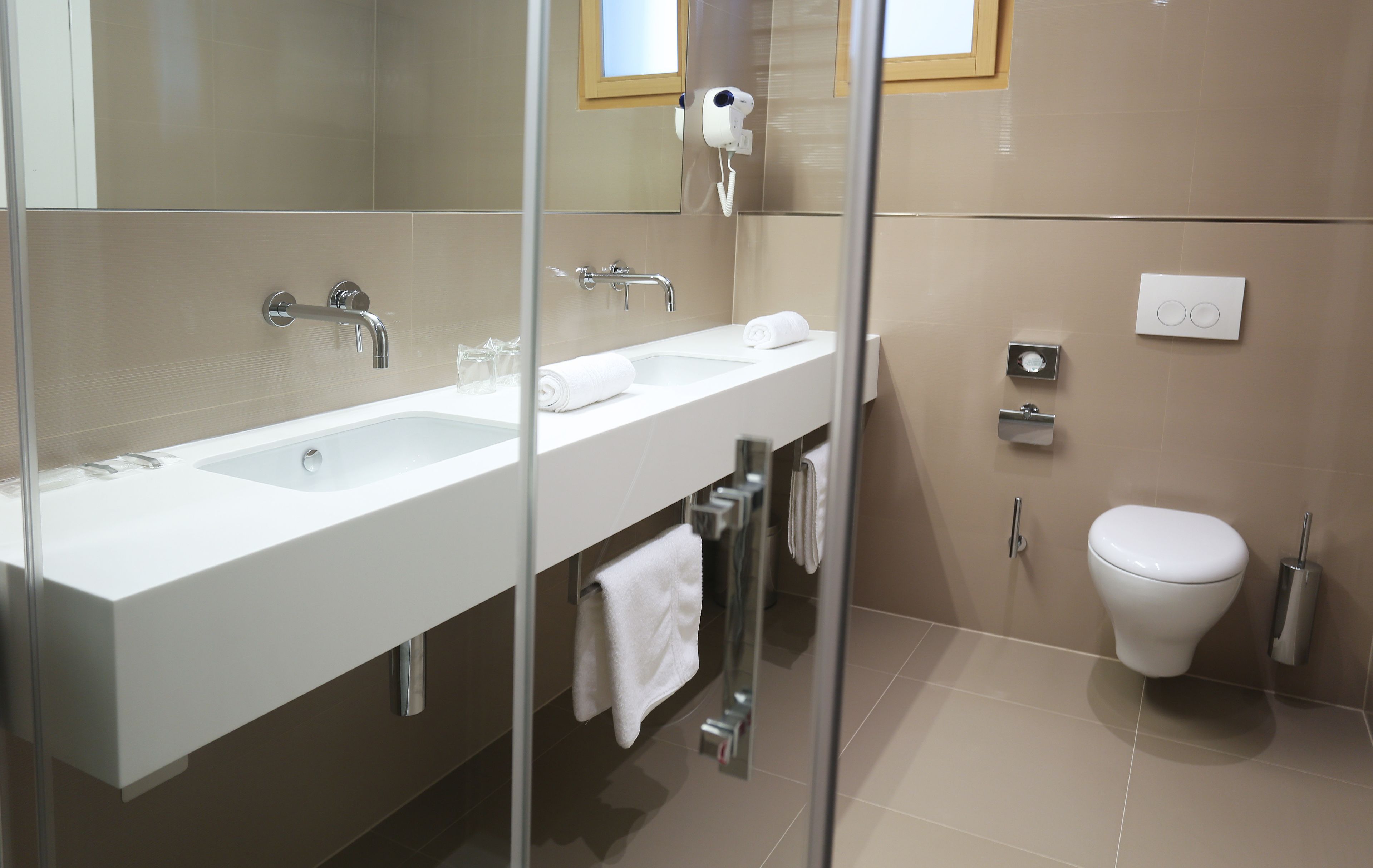Un baño moderno con ducha envuelta en vidrio, un lavabo blanco y un inodoro.