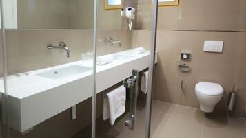 Een moderne badkamer met een douchecabine van glas, een wit wastafelmeubel en een toilet.