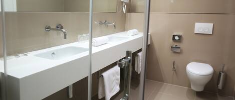 Un baño moderno con ducha envuelta en vidrio, un lavabo blanco y un inodoro.