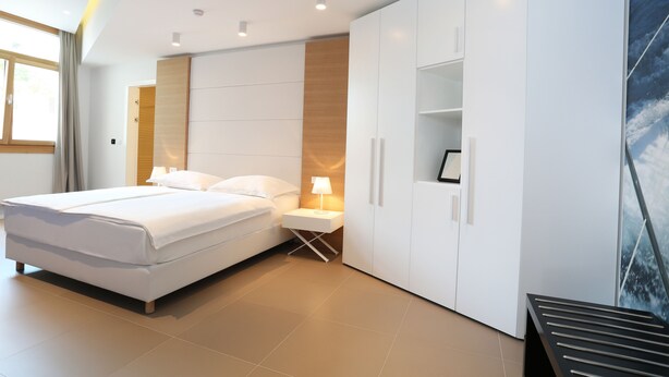 A modern bedroom with a large bed, a nightstand, a wardrobe, and a view of the ocean. - Guesthouse Villa Scalaria (Split)