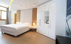 Ein modernes Schlafzimmer mit einem großen Bett, einem Nachttisch, einem Kleiderschrank und Blick auf den Ozean.