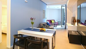 A modern living room with a dining area, featuring a white table, black chairs, and a vase with flowers. - Guesthouse Villa Scalaria (Split)