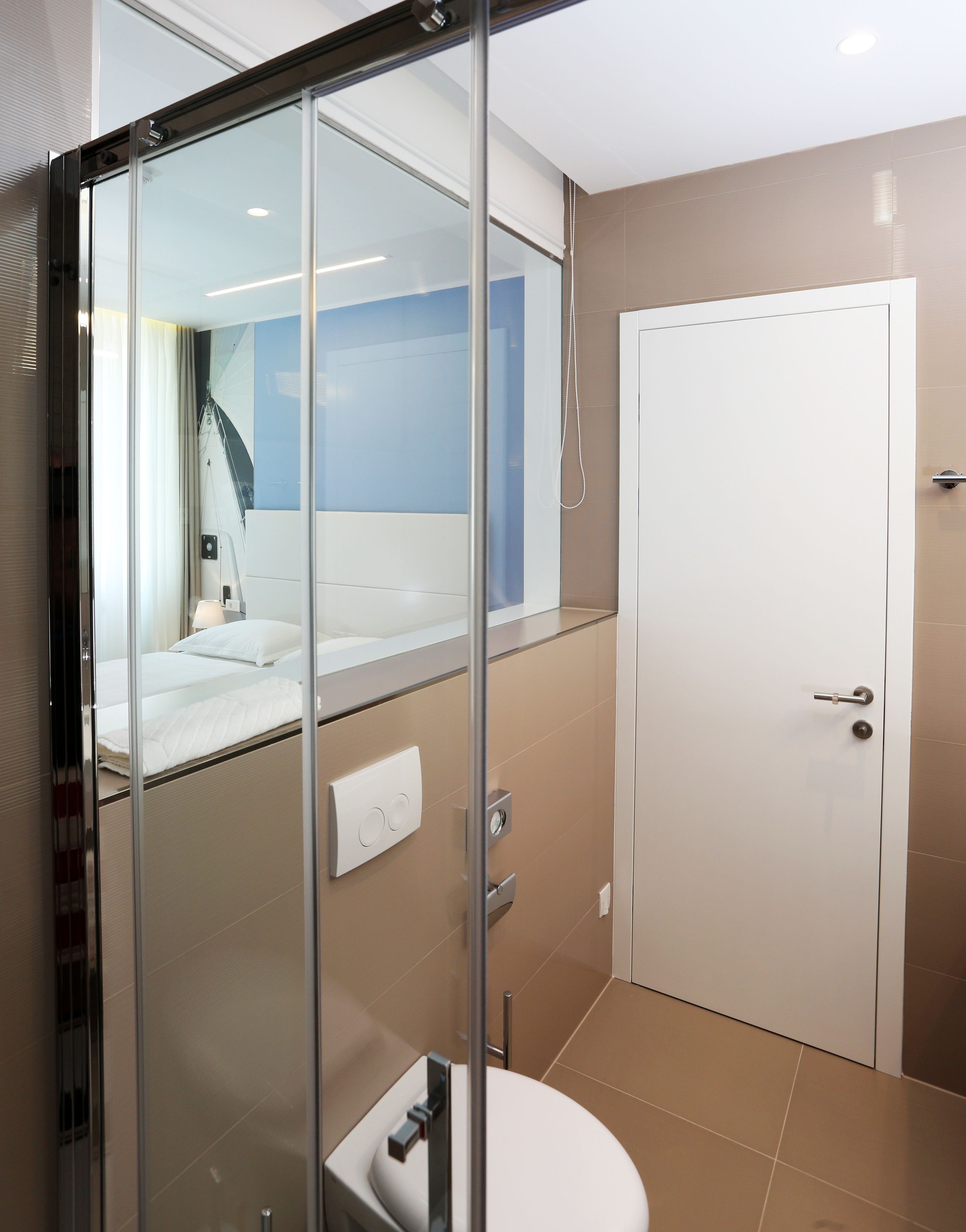 A modern bathroom with a glass shower enclosure, a toilet, and a white door.