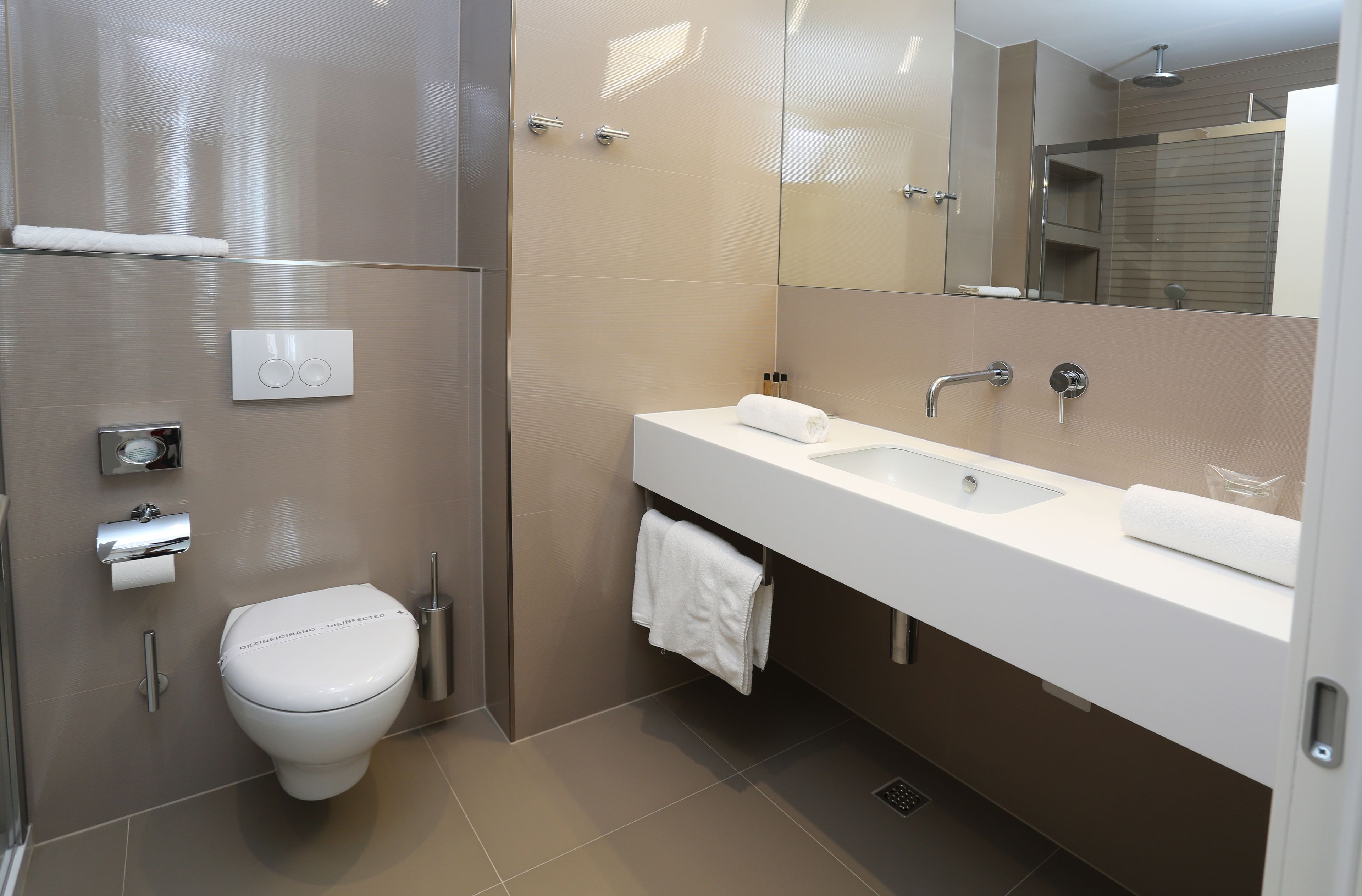 Et moderne badeværelse med toilet, vask og spejl.