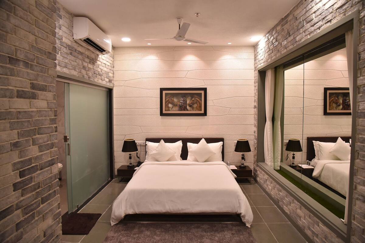 A bedroom with a large bed, two nightstands, a mirror, and a door.