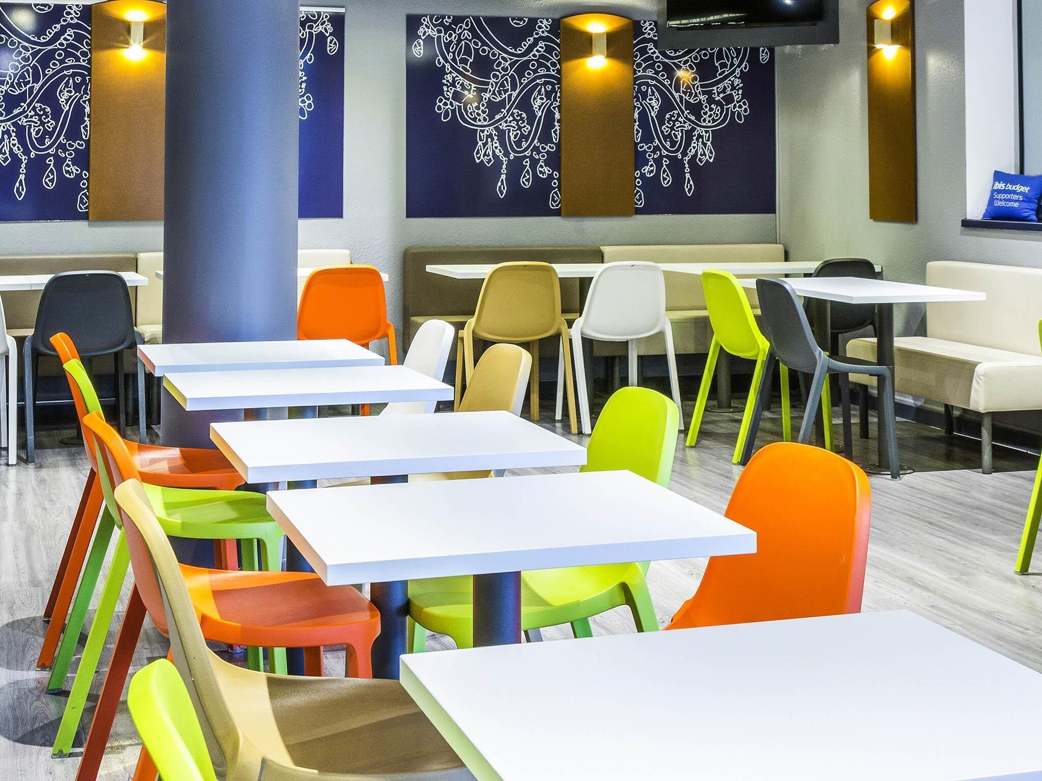 Un comedor con varias mesas y sillas, un pilar y decoración en la pared.
