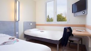 Een hotelkamer met twee bedden, een bureau, een stoel, een televisie en een raam met uitzicht.