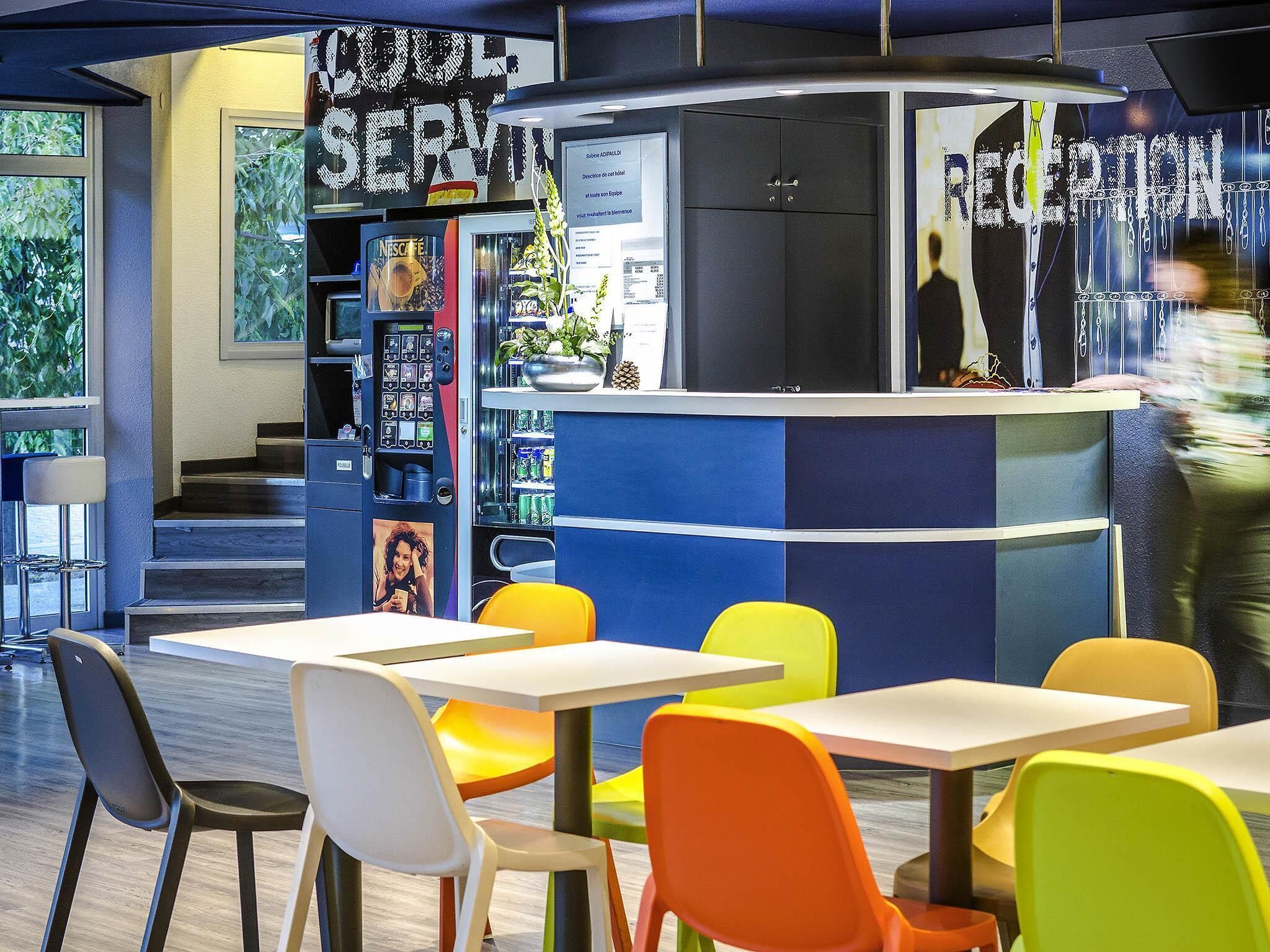Een receptiezone met een balie, zithoek en een trap naar een hoger niveau.
