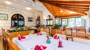 Un restaurant avec des tables et des chaises en bois, des nappes blanches et des serviettes rouges.