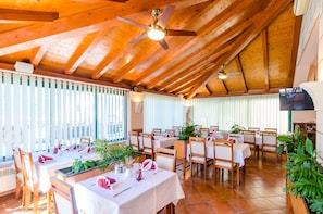 A spacious dining area with wooden beams, white tablecloths, and neatly arranged chairs. - Pansion Srebreno (Zupa dubrovacka)