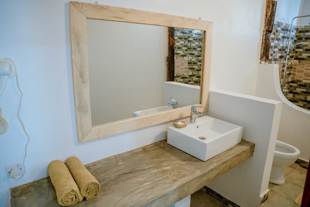 A bathroom with a wooden-framed mirror, a white sink, and a towel on the counter.