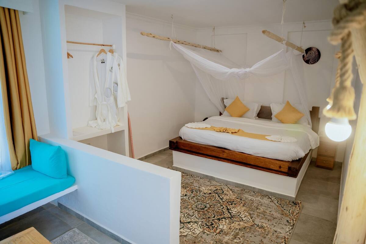 A bedroom with a bed, a bench, a hanging chair, and a canopy bed.