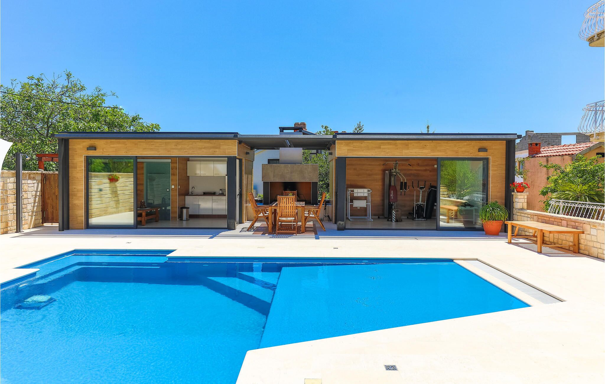 A modern two-story house with a swimming pool, featuring a kitchen, dining area, and a gym.
