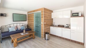 A compact living space with a sofa, a wooden table, a kitchenette, and a TV mounted on the wall. - Cozy apartment in Kastel Stari (Kastel Stari)