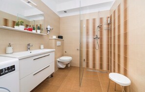A modern bathroom with a glass shower enclosure, a white sink, a toilet, and a small stool. - Cozy apartment in Kastel Stari (Kastel Stari)