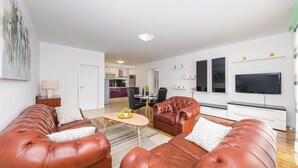 A modern living room with a leather sofa set, a dining area, and a kitchen in the background. - Cozy apartment in Kastel Stari (Kastel Stari)