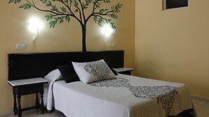 A bedroom with a bed, two bedside tables, a wall-mounted lamp, and a small window. - Hostal Miramar (Barbate)