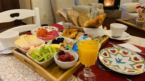 Bandeja de desayuno con pan, pasteles, queso, embutidos, frutas y un vaso de zumo de naranja.