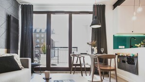 A modern living room with a sofa, coffee table, and dining area. A large window offers a view of the city. - Apartamenty Gdańsk-Old Town Szafarnia 6a (Gdansk)