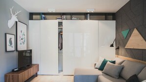 A modern living room with a sofa, coffee table, TV, and a wardrobe. - Apartamenty Gdańsk-Old Town Szafarnia 6a (Gdansk)