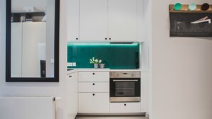 A compact kitchen with white cabinetry, a built-in oven, and a teal backsplash. - Apartamenty Gdańsk-Old Town Szafarnia 6a (Gdansk)